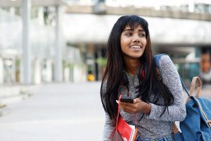 happy Indian university student walking with mobile phone